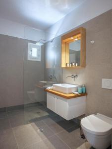 een badkamer met een wastafel, een toilet en een spiegel bij Naxos Aigli Villas-Master villa in Naxos Chora +10 foto's