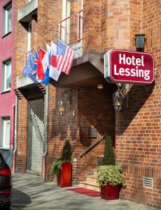 una señal de arrendamiento de hotel en un lado de un edificio con banderas en Hotel Lessing en Düsseldorf