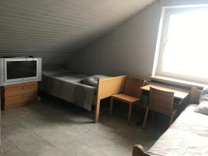 a small room with a bed and a table and a tv at Pension JuRa in Gronau
