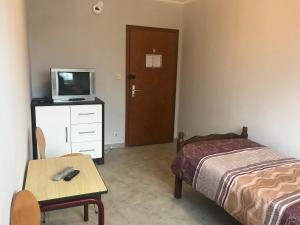a bedroom with a bed and a tv on a dresser at Pension JuRa in Gronau
