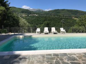 a swimming pool with three chairs at Casa Elena in Camporgiano