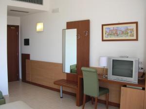 Zimmer mit einem Schreibtisch, einem TV und einem Spiegel in der Unterkunft Hermes Hotel in Policoro