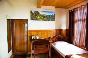 a bedroom with a bed and a desk and a table at Dreamhome Stay in Kurseong