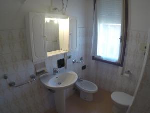 un bagno bianco con lavandino e WC di Condominio Commerciale a Caorle Altre 19 foto