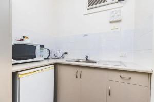 uma cozinha com um lavatório e um micro-ondas em Hi 5 Glenelg Studio Apartment em Glenelg