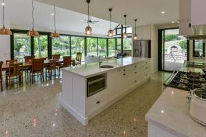 a kitchen with white cabinets and a dining room at Elm Tree Lodge Beechworth in Beechworth