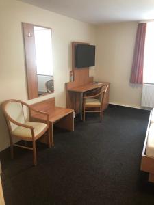 ein Hotelzimmer mit einem Schreibtisch, einem Tisch und Stühlen in der Unterkunft Döbelts Hotel Schützenhaus Jessen in Jessen