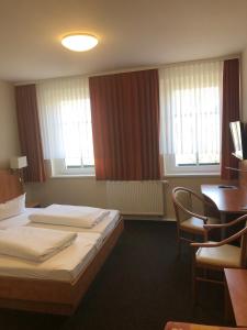 a hotel room with two beds and a desk at Döbelts Hotel Schützenhaus Jessen in Jessen