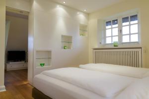 two beds in a bedroom with a tv and a window at Appartementhaus Lüüvhoog in Keitum