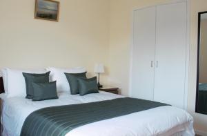 um quarto com uma grande cama branca com almofadas verdes em The Glebe, Am Fasgadh em Bowmore