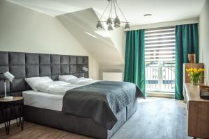1 dormitorio con 1 cama grande y cortinas verdes en Apartamenty Leśna 1, en Zielona Góra
