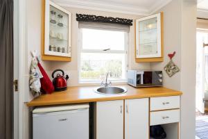 a kitchen with white cabinets and a sink and a window at Sandpiper's Nest - Hout Bay in Hout Bay