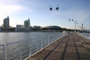 a boardwalk next to a body of water with a city at Charming Apartment with Balcony & Pool in Lisbon