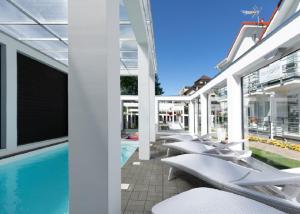 a row of white lounge chairs next to a swimming pool at Palisander z widokiem na morze in Trzęsacz