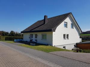una casa blanca con techo negro en una calle en Ferienwohnung Kittel, en Oberzissen