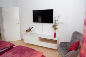 sala de estar con TV en una pared blanca en First Floor Olching, en Olching