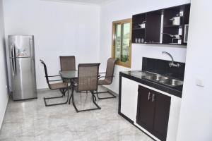 a kitchen with a sink and a table and a refrigerator at Hôtel La Couronne RW in Yaoundé
