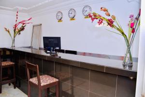 a lobby with a reception desk with clocks on the wall at Hôtel La Couronne RW in Yaoundé