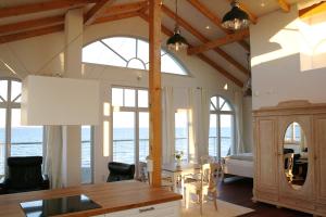 a living room with a table and chairs and windows at Strandhuus - Urlaub aan de Ostsee in Timmendorfer Strand