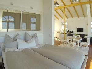 a bedroom with a large white bed and a dining room at Strandhuus - Urlaub aan de Ostsee in Timmendorfer Strand