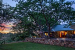 a house with a stone wall and a tree at Sangasava Safari Lodge in Balule Game Reserve