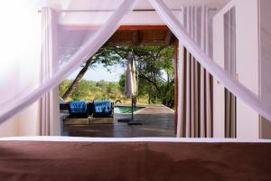 a bedroom with a bed and two chairs and an umbrella at Sangasava Safari Lodge in Balule Game Reserve
