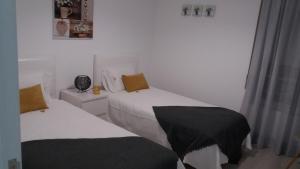 a bedroom with two beds with black and white sheets at Sunset House Azores in Ponta Delgada