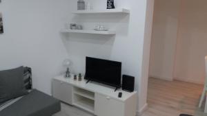 a living room with a flat screen tv on a white wall at Sunset House Azores in Ponta Delgada