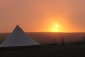 a tent in a field with the sunset in the background at Wold Farm Bell Tents in Flamborough