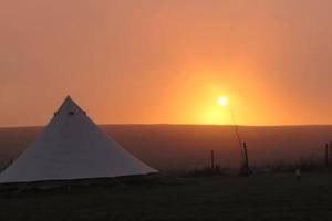 a tent in a field with the sunset in the background at Flamborough Glamping Bell Tents in Flamborough