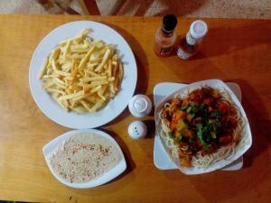 a table with two plates of pasta and a bowl of fries at Sheikh Mousa Bedouin camp in Saint Catherine