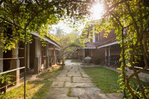 Un camino de piedra entre dos edificios con el sol brillando. en Villa Araliya, en Negombo