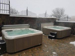 2 bains à remous sur une terrasse dans la neige dans l'établissement Family Hotel Emaly Green, à Sapareva Banya