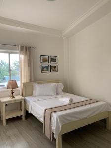 a white bedroom with a large bed and a window at Isaguirre's Pension House in Baler