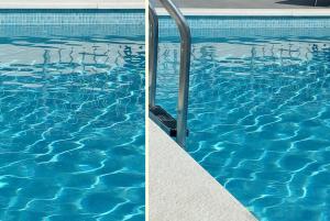 a blue swimming pool with blue water and a metal railing at House Lucia in Brštanovo