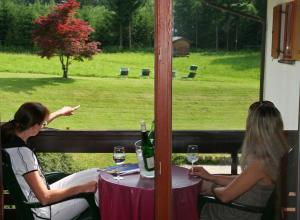 zwei Frauen, die an einem Tisch sitzen und aus dem Fenster schauen in der Unterkunft Hotel Garni Pension zur Wacht in Strobl