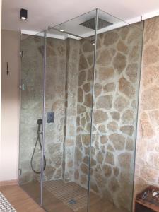 a shower in a room with a stone wall at aznalmara loft rural in Benaocaz