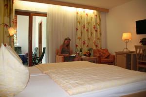 Hotel Garni Pension zur Wacht في شتروبل: امرأة جالسة في غرفة مع سرير
