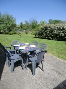 a table with four chairs and a table and chairs at Le Refuge in Champagné-Saint-Hilaire