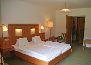 ein Schlafzimmer mit einem großen Bett mit weißer Bettwäsche in der Unterkunft Hotel Garni Pension zur Wacht in Strobl