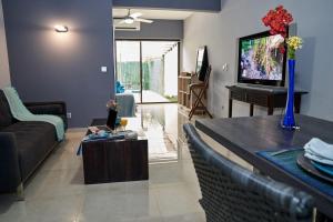 a living room with a couch and a tv at Appartements Cayenne Standing in Cayenne