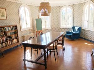 een eetkamer met een tafel, stoelen en ramen bij Espectacular Casa Chateau en el centro de Olot in Olot