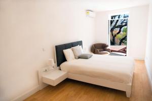 a white bedroom with a bed and a window at Finest Rentals - Downtown Villa in Funchal