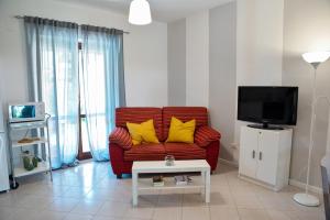 Villa Porto Ada Residence في بيتسو: غرفة معيشة مع أريكة حمراء مع وسائد صفراء