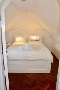 1 cama con sábanas blancas y almohadas en una habitación en Cavalli's Cottage, en Bilthoven