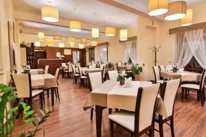 a restaurant with white tables and chairs and a piano at Hotel Kantoria in Tarnów