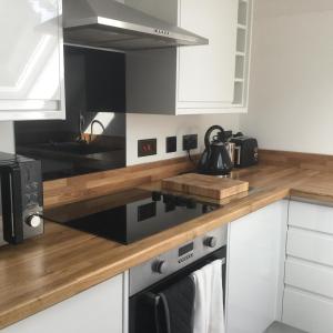 a kitchen with white cabinets and a wooden counter top at Idyllic Studio Flat in Winchester