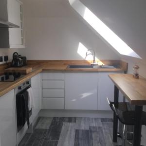 cocina con armarios blancos, fregadero y mesa en Idyllic Studio Flat en Winchester