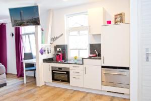 a kitchen with white cabinets and a window at Ferienwohnung Siebenstern Jena in Jena