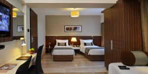 a hotel room with two beds and a television at Residency Sarovar Portico in Mumbai